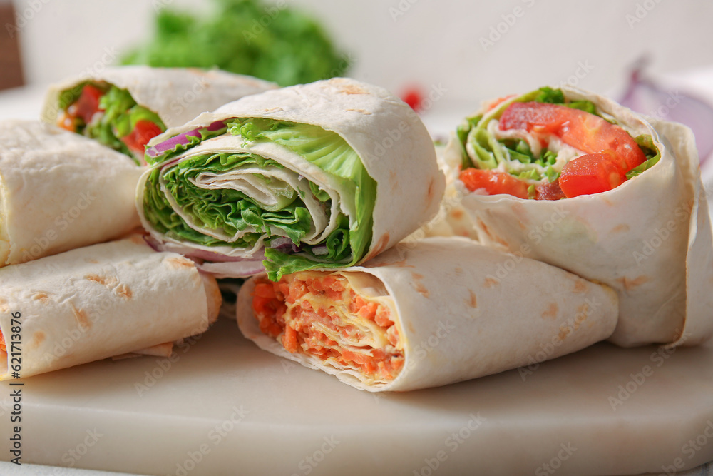 Board of tasty lavash rolls with vegetables on table