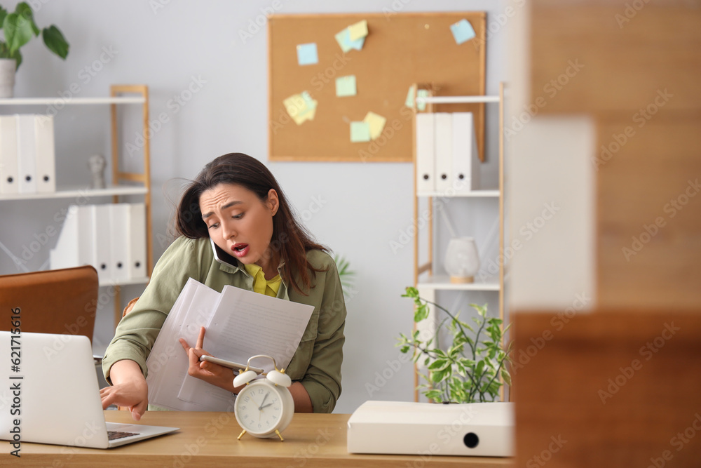 Stressed young businesswoman working under deadline in office