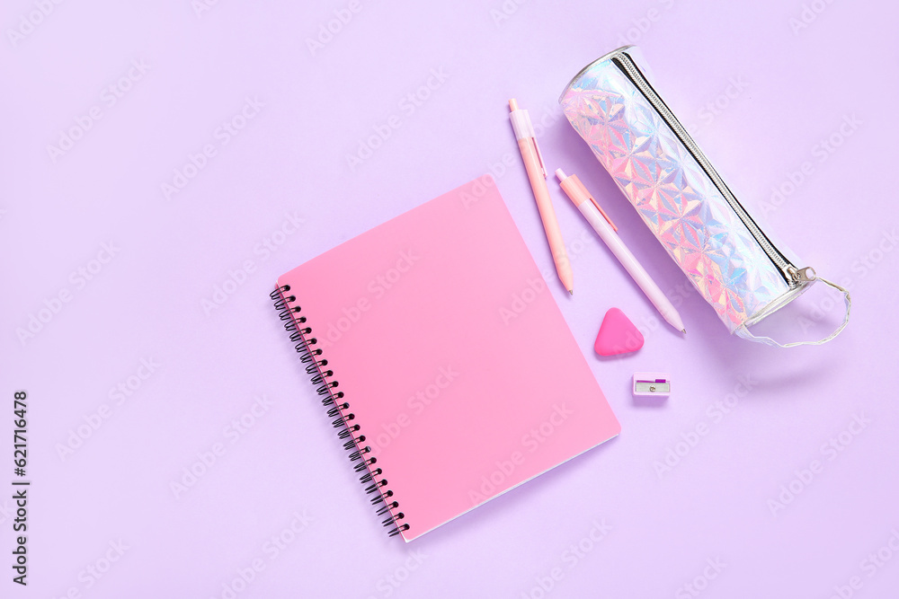 Notebook with pencil case and different stationery on lilac background