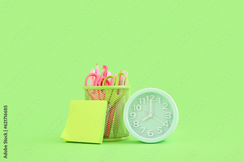 Alarm clock with different stationery on green background