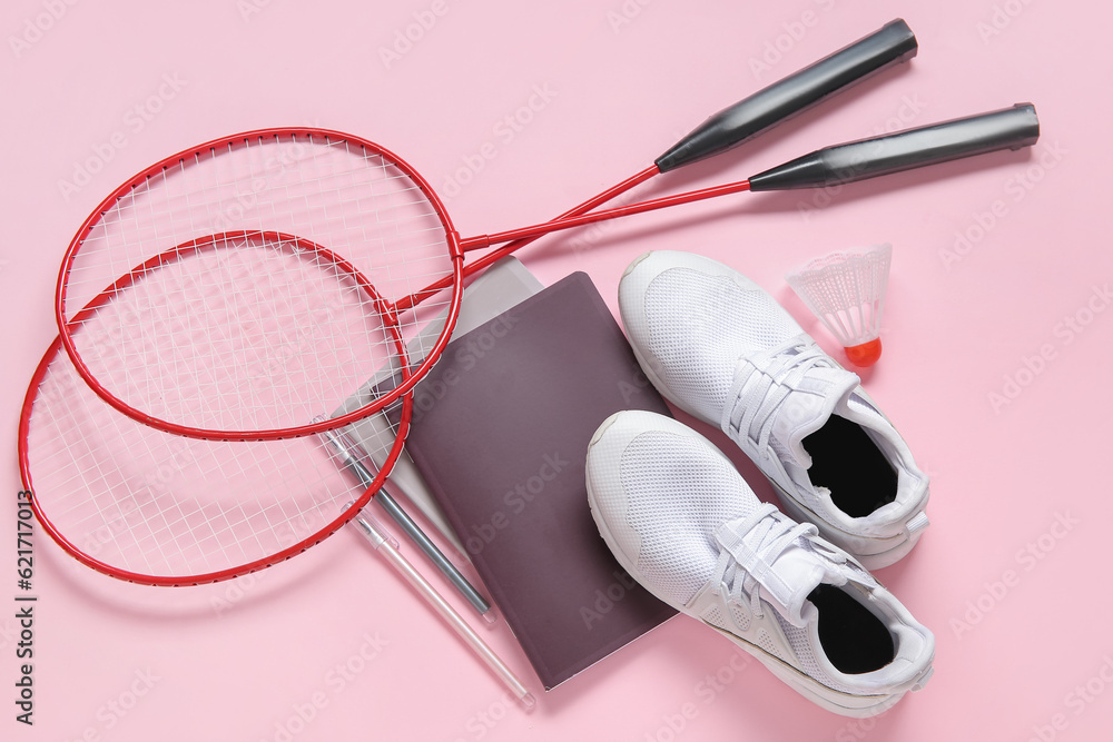 Sneakers with badminton shuttlecock, rackets and stationery on pink background