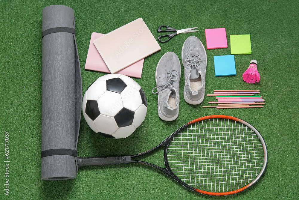 Sneakers with sport equipment and different stationery on color background