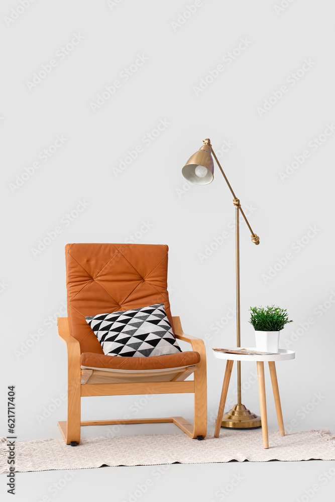 Armchair with table, lamp and rug on white background