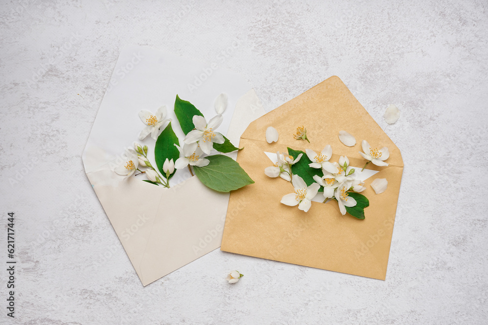 Composition with envelopes and beautiful jasmine flowers on light background