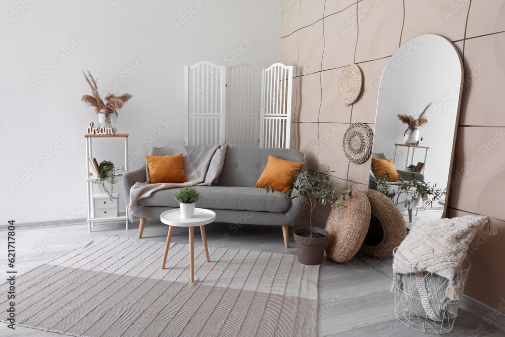 Interior of living room with grey sofa, coffee table and mirror