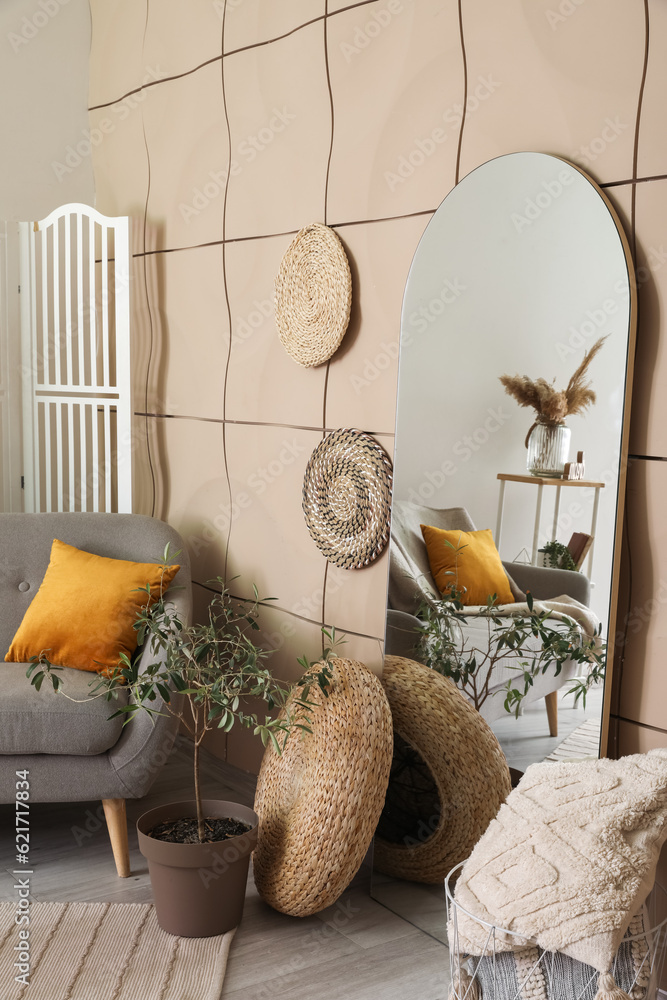 Interior of living room with mirror, houseplant and grey sofa