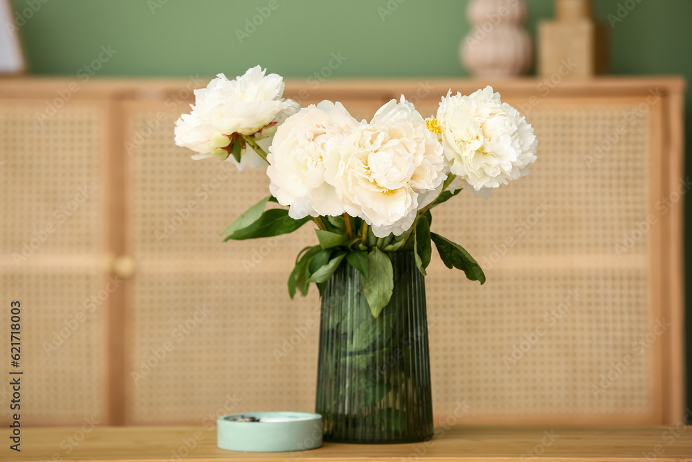 Vase of white peonies with candle on coffee table in living room