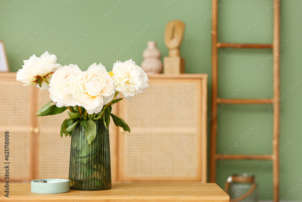 Vase of white peonies with candle on coffee table in living room