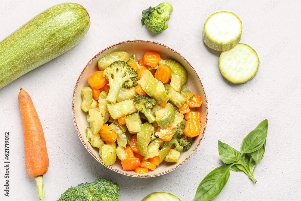 Bowl with different vegetables on light background