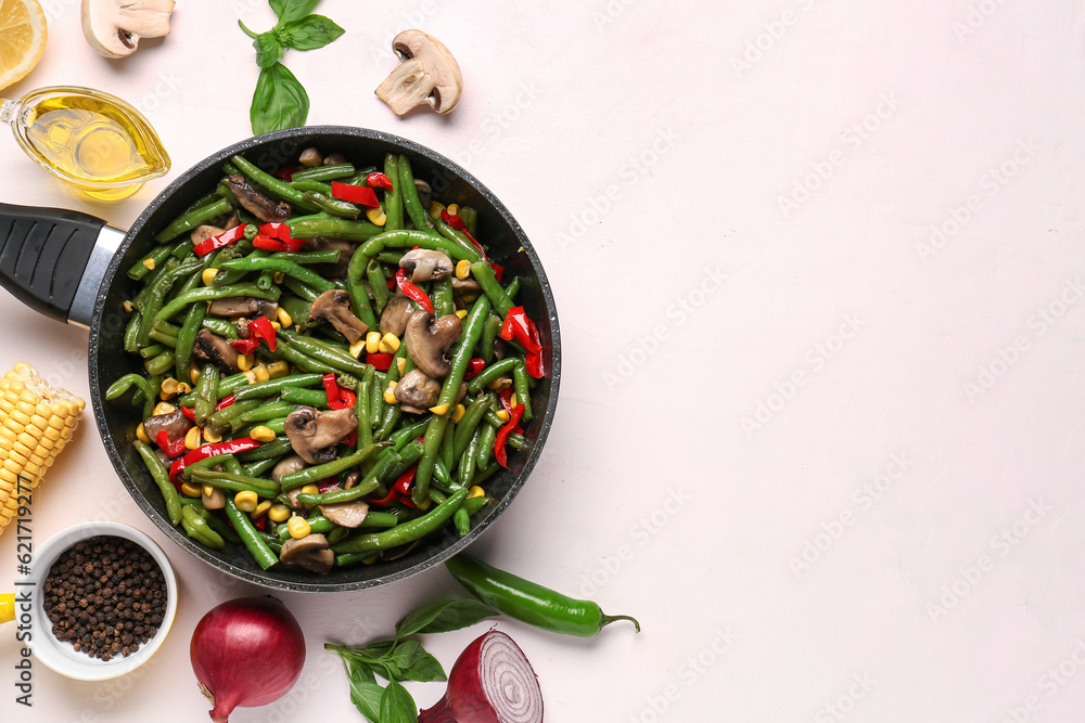 Frying pan with different vegetables on light background