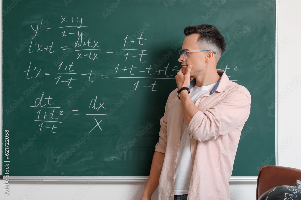 Thoughtful Math teacher near chalkboard in classroom