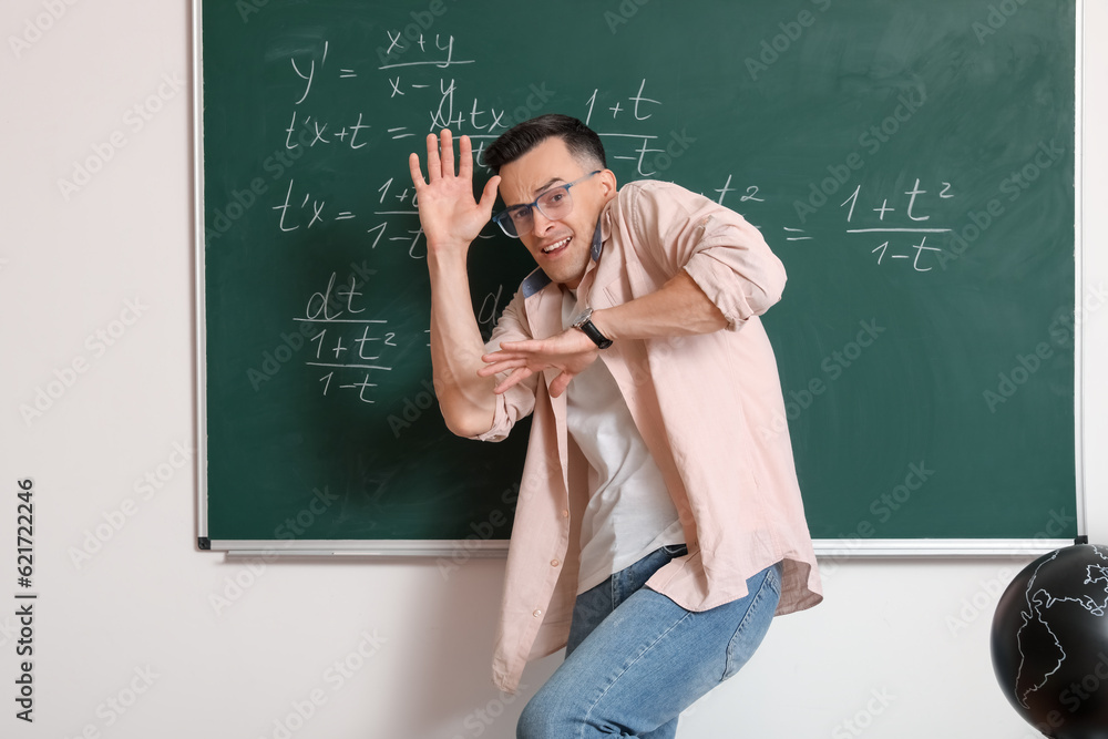 Scared Math teacher near chalkboard in classroom