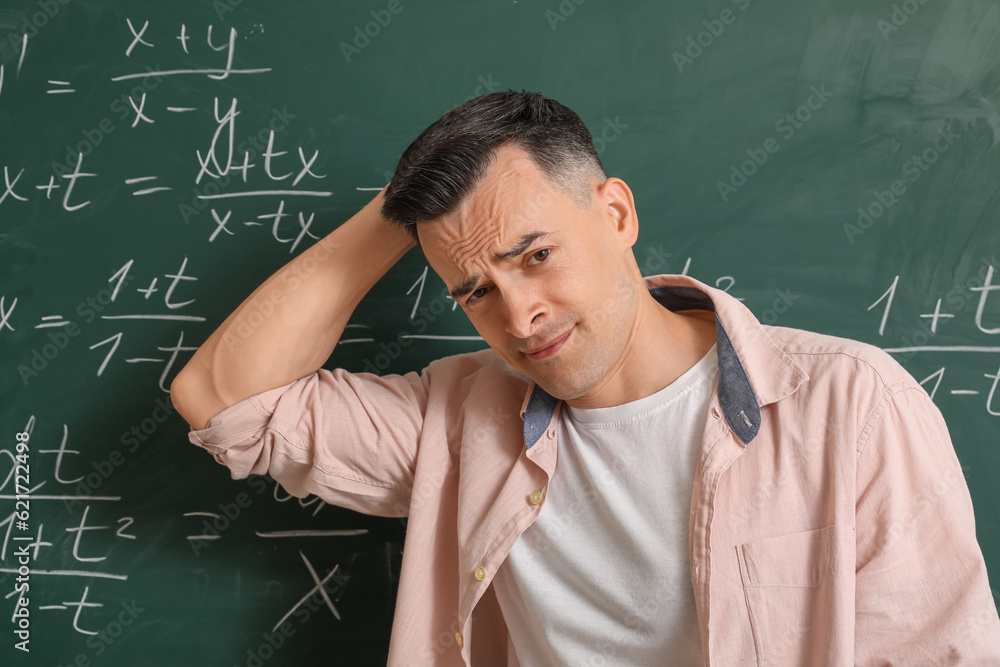 Tired Math teacher near chalkboard in classroom