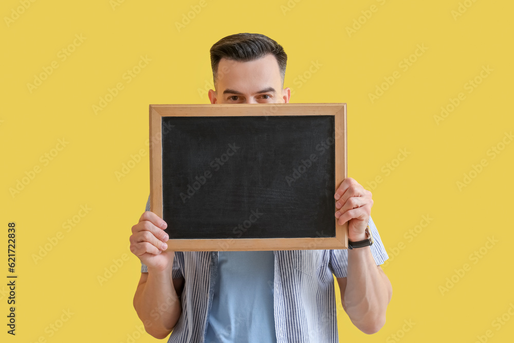 Male teacher with chalkboard on yellow background