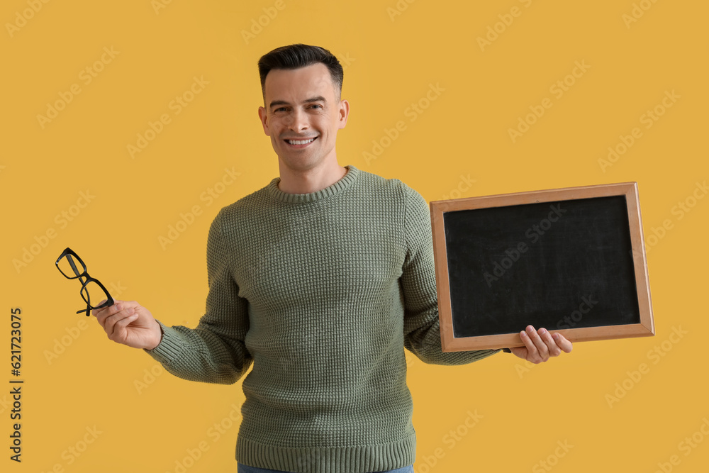 Male teacher with chalkboard and eyeglasses on yellow background