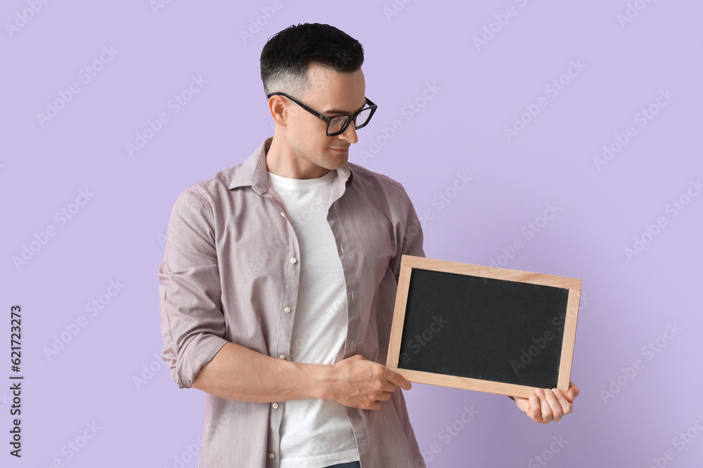 Male teacher with chalkboard on lilac background