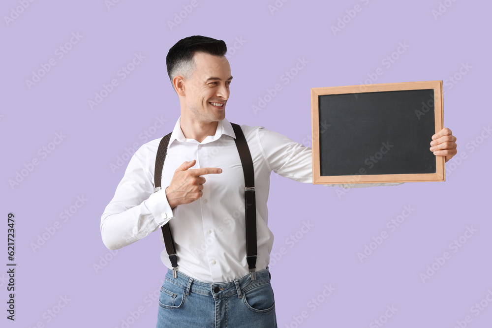 Male teacher pointing at chalkboard on lilac background