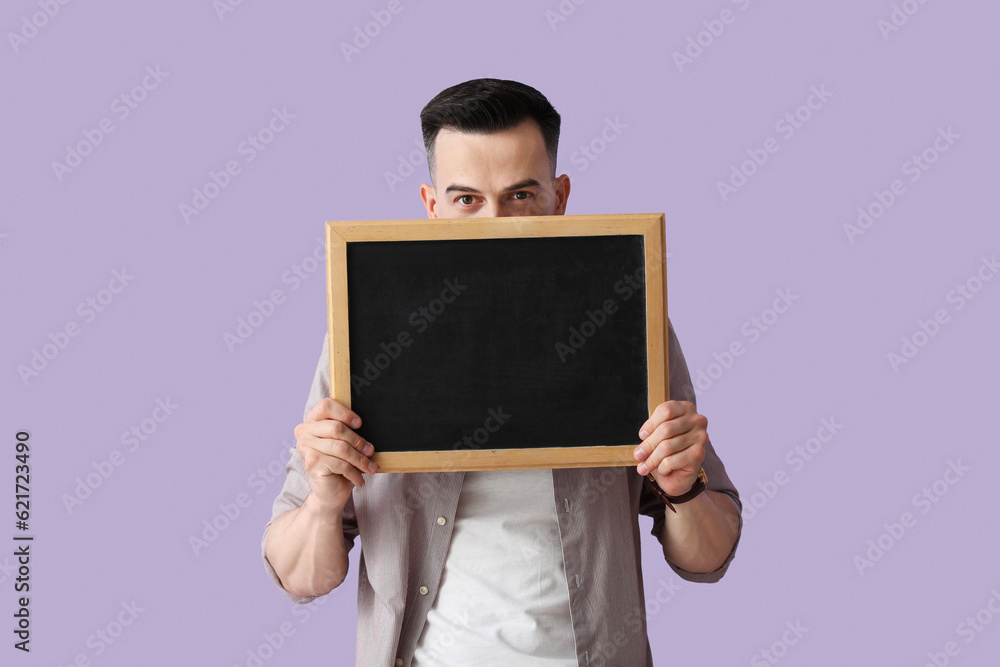 Male teacher with chalkboard on lilac background