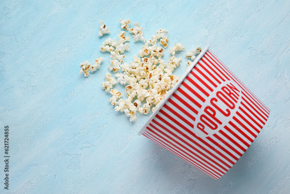 Bucket with tasty popcorn on blue background