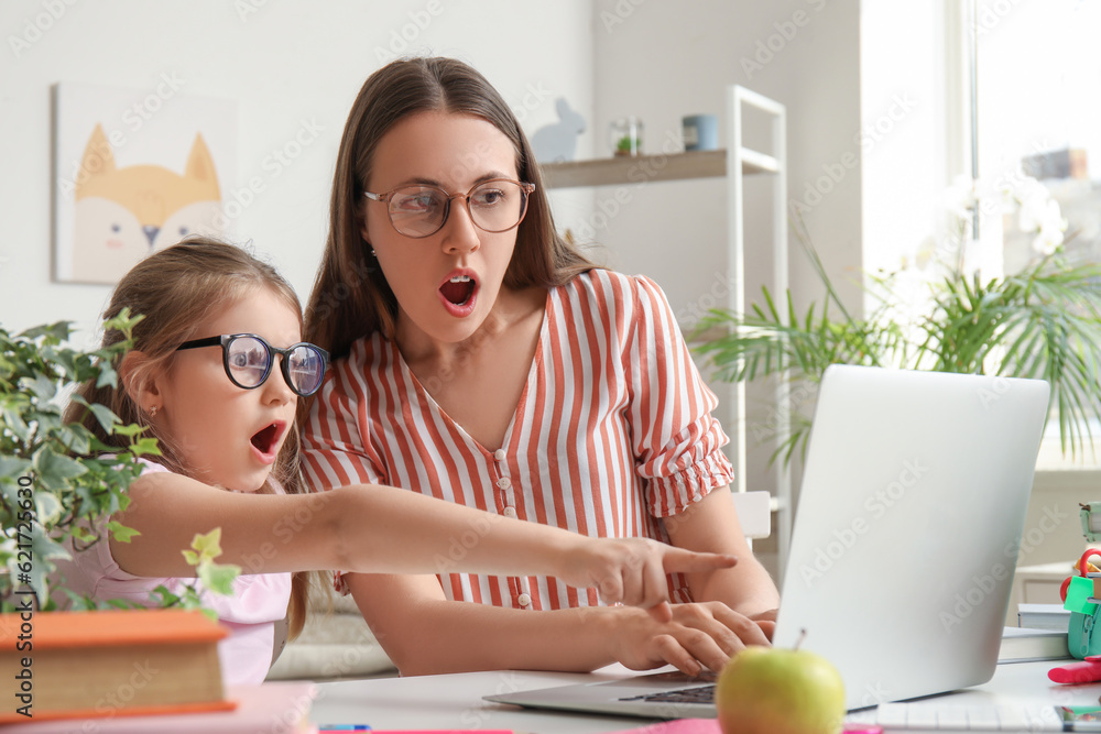 Shocked little girl doing lessons with her mother at home