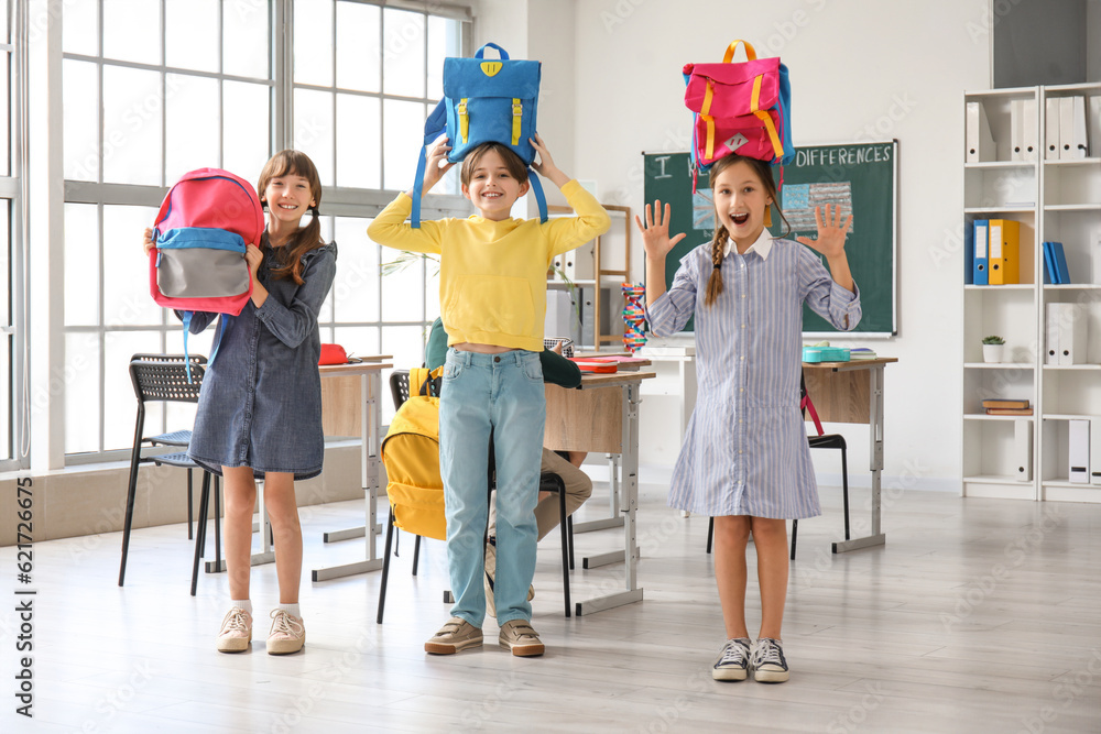 Little pupils with backpacks in classroom