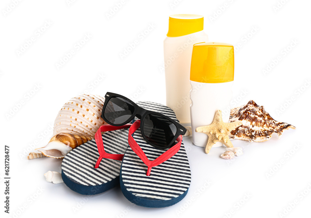 Sunglasses with flip flops, seashells and bottles of sunscreen cream isolated on white background