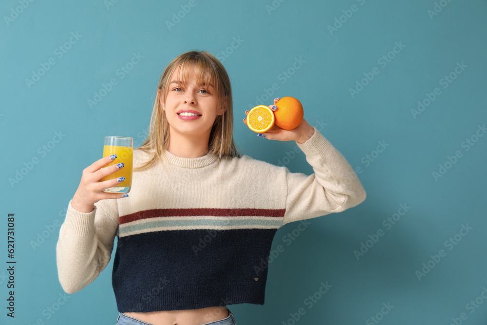 Teenage girl with glass of juice and oranges on blue background