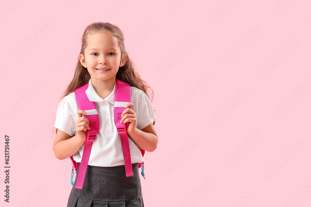 Little schoolgirl with backpack on pink background