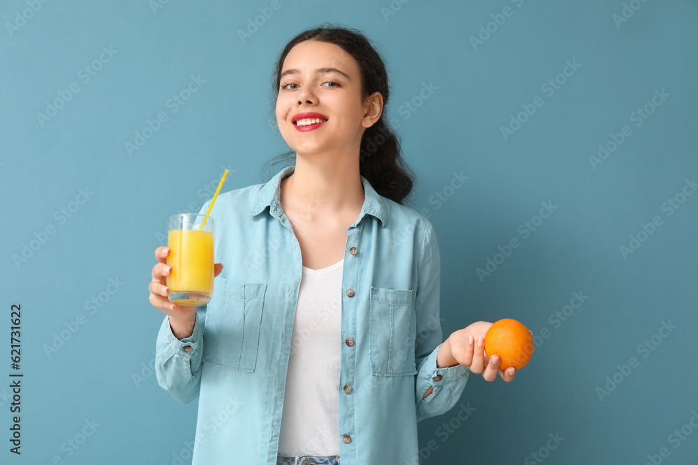 Teenage girl with glass of juice and orange on blue background