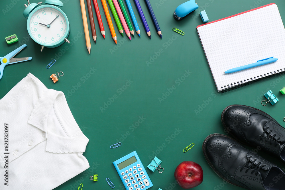 Frame made of stylish school uniform with alarm clock and different stationery on green chalkboard