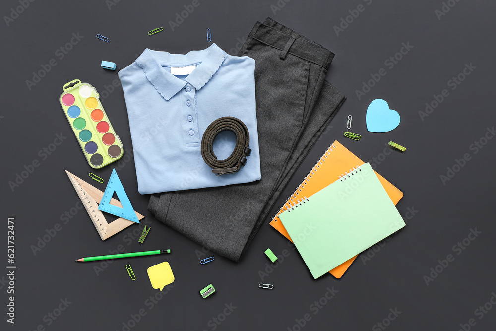 Stylish school uniform with different stationery on black chalkboard