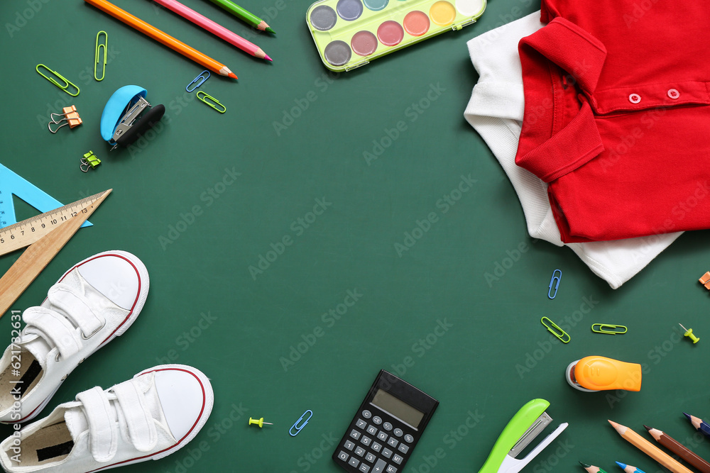 Frame made of stylish school uniform and different stationery on green chalkboard