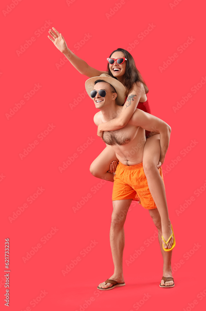 Young couple in sunglasses on red background