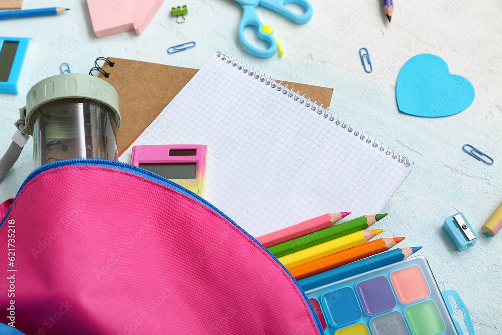 Backpack with blank notebook and different stationery on color background