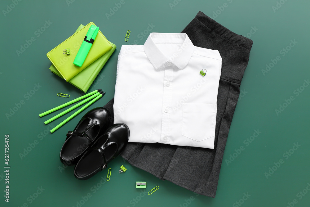 Different stationery and stylish school uniform on green chalkboard