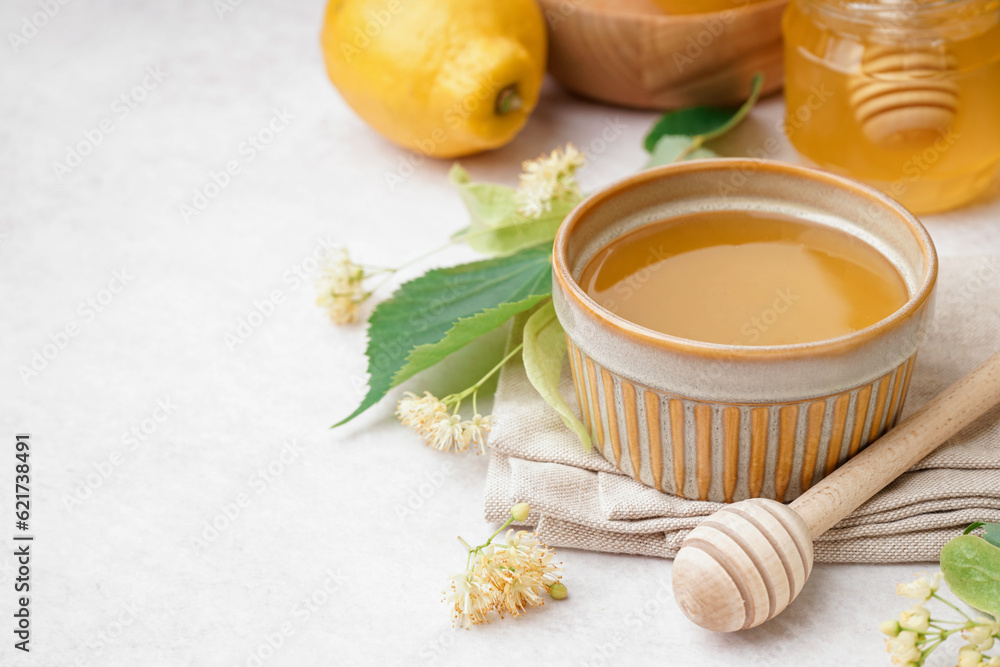 Bowl with linden honey and dipper on white background