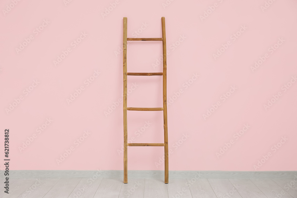 Wooden ladder near pink wall in room