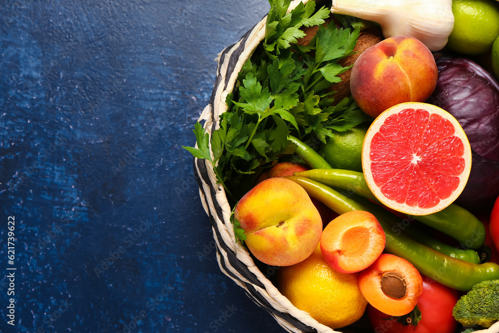 Wicker bowl with different fresh fruits and vegetables on blue background, closeup