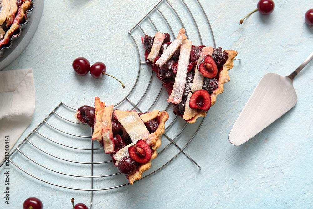 Stand with pieces of tasty cherry pie on blue background