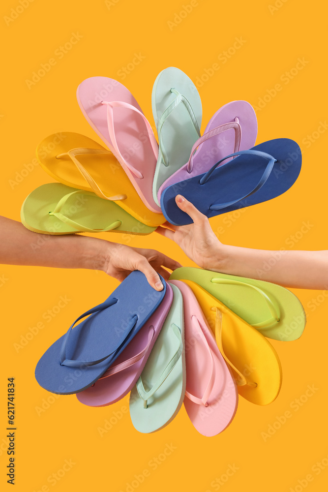 Hands with many flip-flops on yellow background