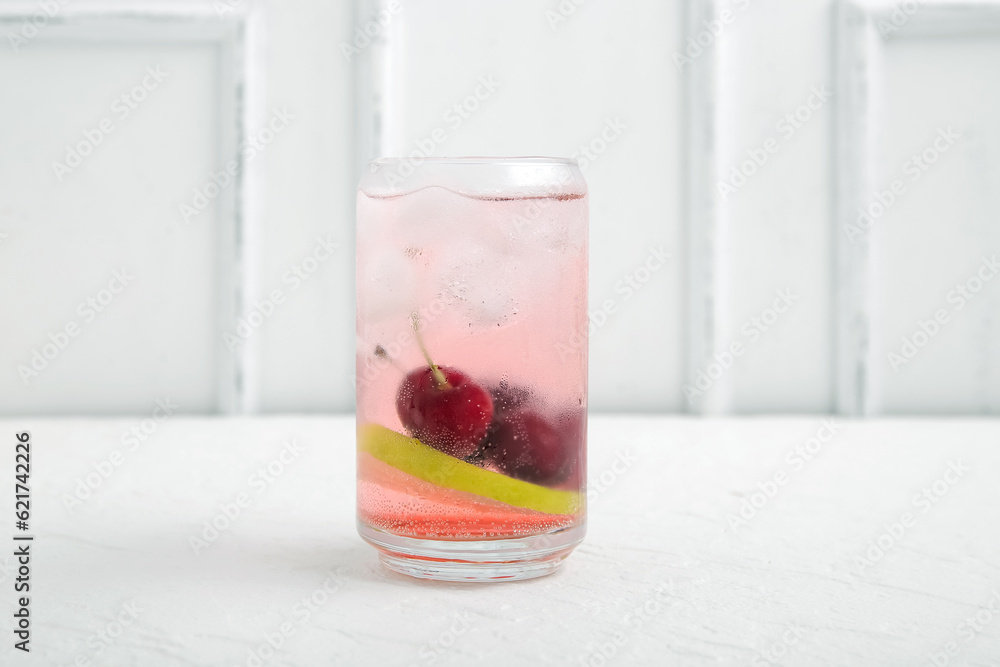 Glass of tasty cherry lemonade with lime on white background