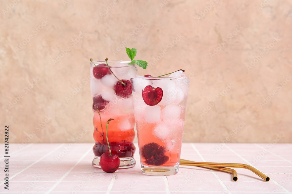 Glasses of tasty cherry lemonade with mint on pink tile table