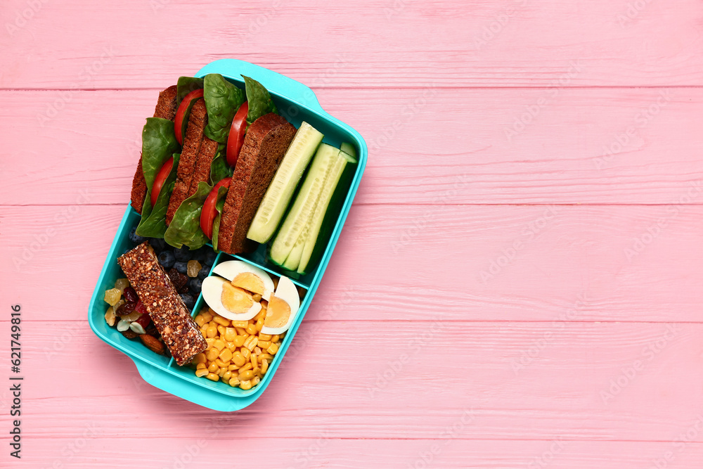 Lunchbox with tasty food on pink wooden background