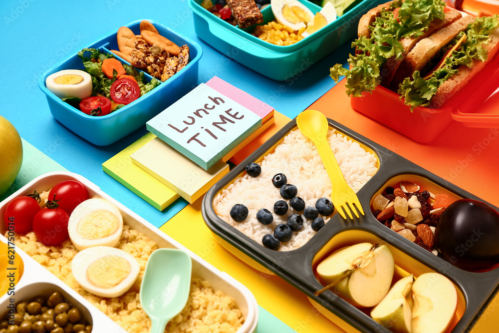 Different tasty food in lunchboxes and sticky notes with text LUNCH TIME on color background