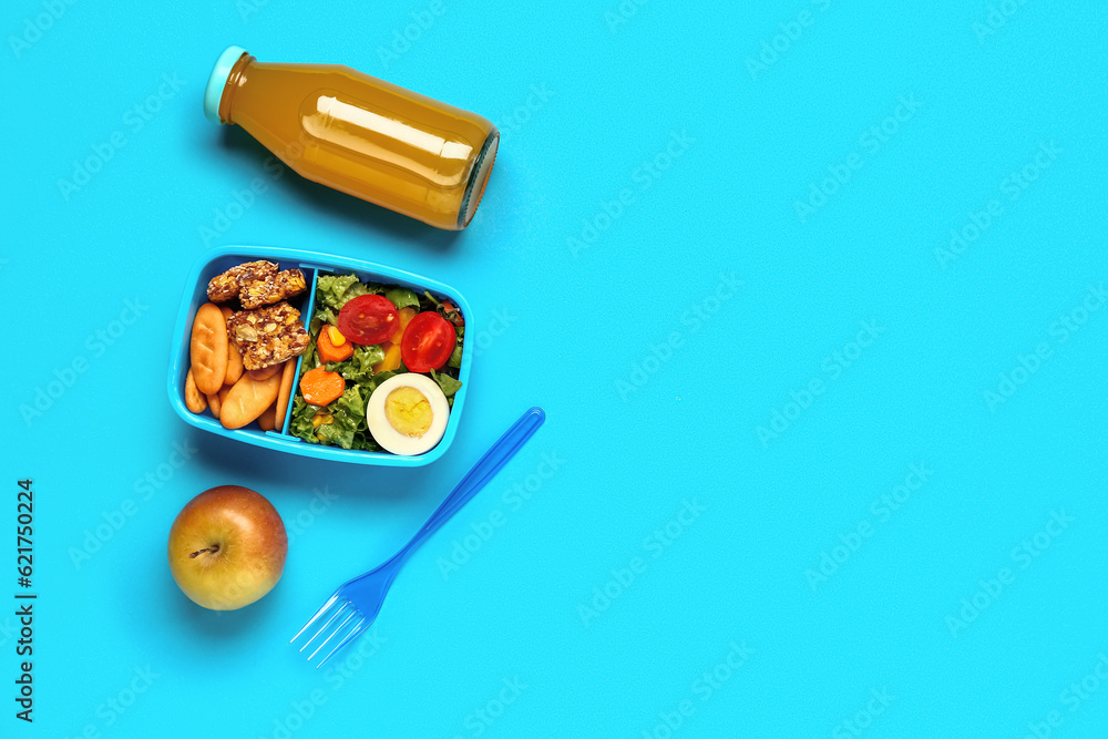 Bottle of juice and lunchbox with tasty food on blue background