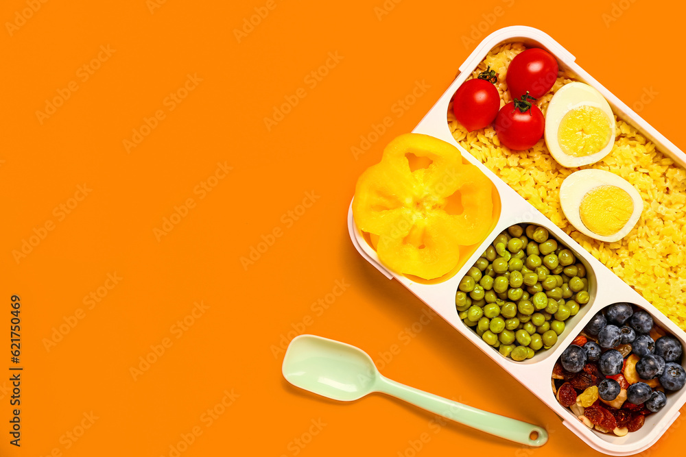 Spoon and lunchbox with tasty food on orange background