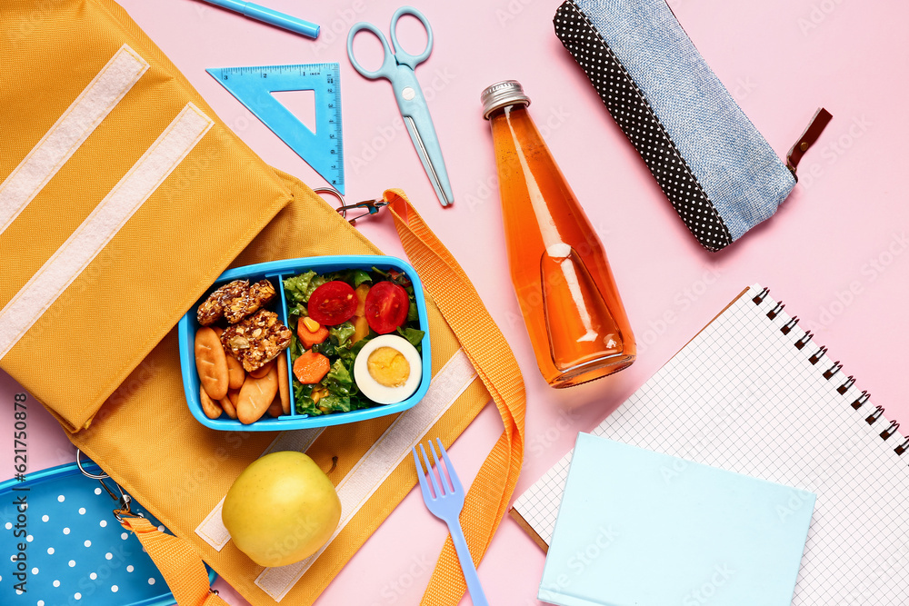 Backpack, stationery, bottle of lemonade and lunchbox with tasty food on pink background