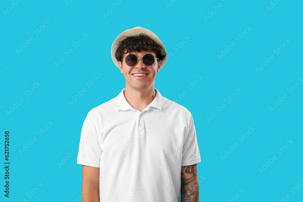 Young man in summer hat and sunglasses on blue background