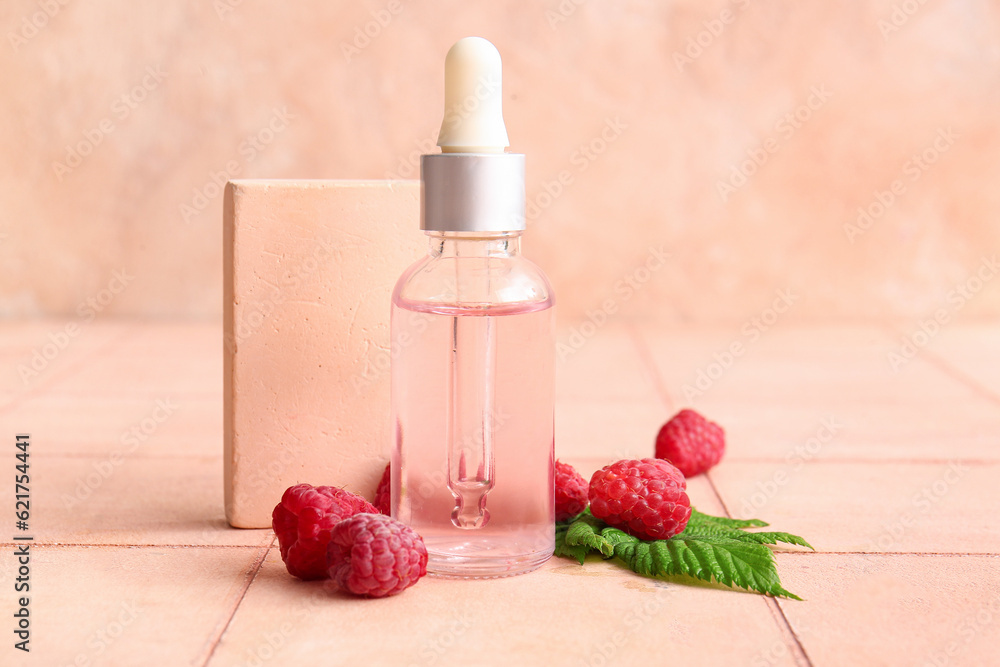 Bottle of cosmetic raspberry oil on pink tile table