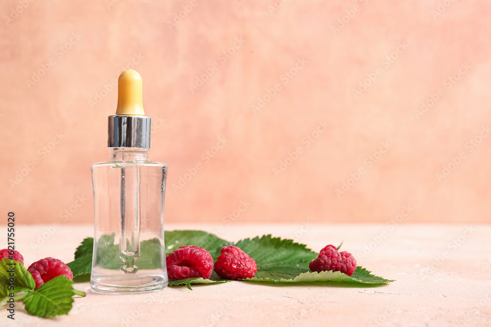 Bottle of cosmetic raspberry oil on pink table